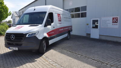 Weißer Mercedes Sprinter mit Kinast Kirchenstühle-Branding vor dem Firmengebäude