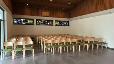Reihen von Kirchenstühlen mit grünen Sitzpolstern in hellem Kirchenraum
